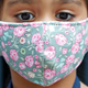 A young girl sports a floral protective mask.